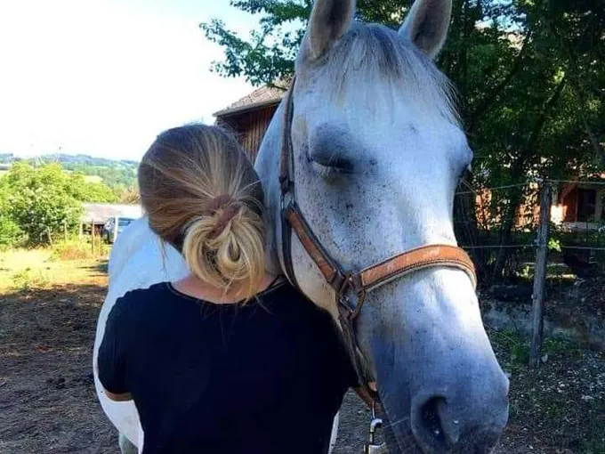 Lydie Autrand près de la tête d'un cheval gris