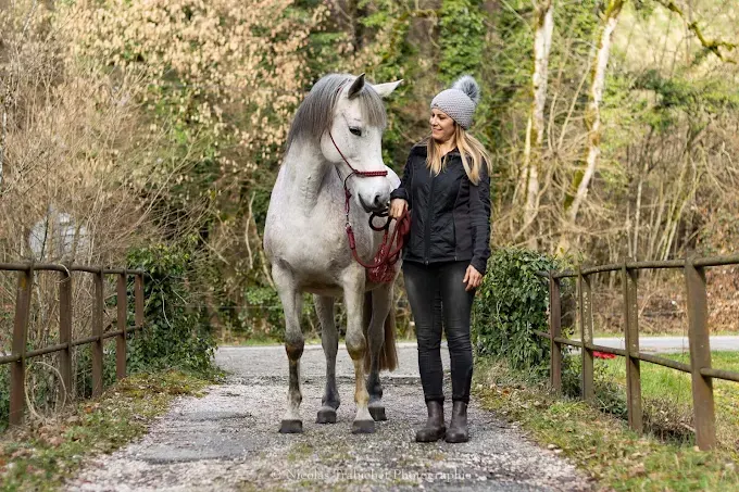 Lydie Autrand aux côtés d'un cheval blanc sur un chemin